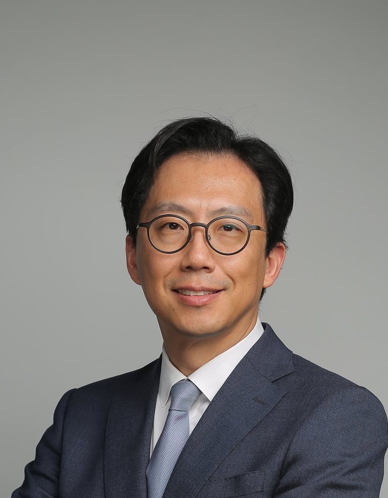짙은 정장 차림으로 팔짱 낀 최문섭 원장(회색 바탕)